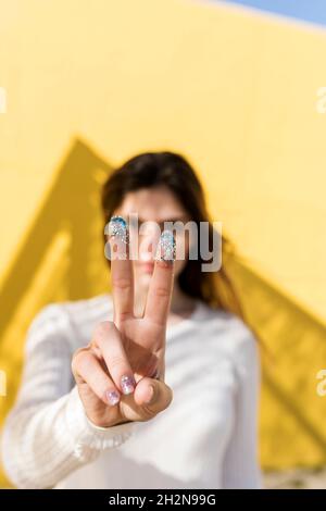 Femme signe de paix avec paillettes sur les doigts Banque D'Images