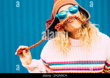 Femme joueur portant des lunettes de soleil faisant de la moustache à partir d'un chapeau en tricot Banque D'Images