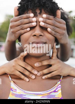 Jeunes amies féminines couvrant la bouche et les yeux d'une femme afro Banque D'Images