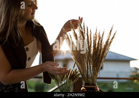 Jeune femme touchant l'herbe sèche dans le pot de fleur Banque D'Images