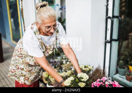 Fleuriste mature et heureuse utilisant une tablette numérique dans un fleuriste Banque D'Images