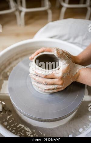 Jeune femme potter moulant de l'argile sur la roue de poterie Banque D'Images