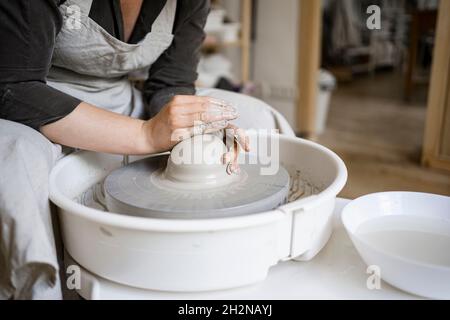 Femelle potter moulant de l'argile sur la roue de poterie dans l'atelier Banque D'Images