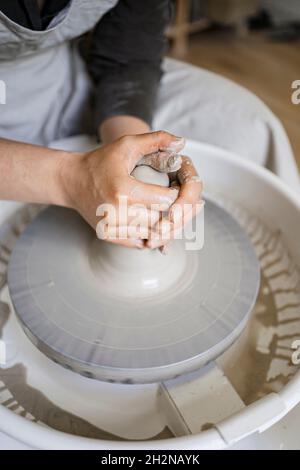 Jeune femme potter moulant de l'argile sur la roue de poterie dans l'atelier Banque D'Images