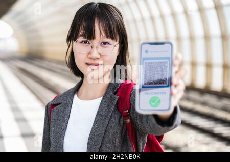 Une adolescente présentant un certificat de vaccination sur l'écran du smartphone au métro Banque D'Images