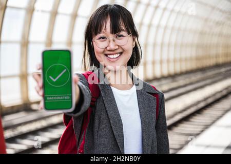 Femme souriante montrant un certificat de vaccination à la station de métro Banque D'Images