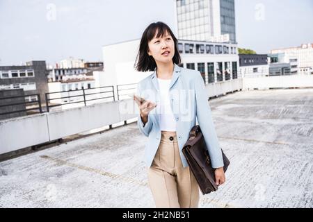 Femme professionnelle avec téléphone mobile et porte-documents sur le toit Banque D'Images