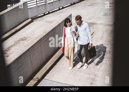 Hommes et femmes professionnels partageant leur téléphone mobile lors de leurs déplacements sur le toit Banque D'Images