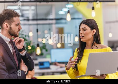 Le responsable explique à son employé comment terminer ses tâches. Collègues discutant d'un projet en se tenant dans un bureau. Banque D'Images