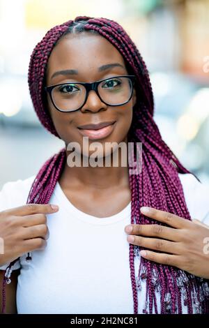 Jeune femme souriante avec des cheveux tressés portant des lunettes Banque D'Images