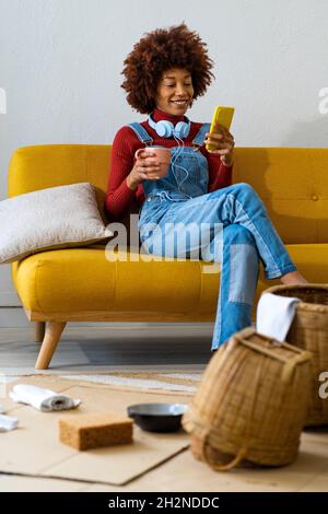 REDHEAD femme écoute de la musique à travers les écouteurs tout en nettoyant le panier à la maison Banque D'Images