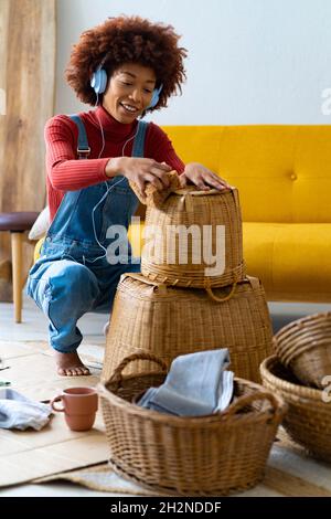 Femme portant un casque nettoyant panier en osier dans la salle de séjour Banque D'Images