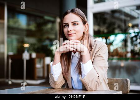 Jeune femme d'affaires avec les mains classed assis sur la terrasse du café Banque D'Images