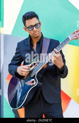 Musicien masculin portant des lunettes jouant de la guitare Banque D'Images