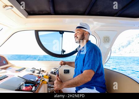 Homme portant un chapeau conduisant un bateau à moteur Banque D'Images