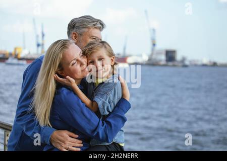 Un fils souriant embrassant mère et père Banque D'Images