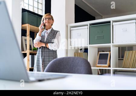Femme d'affaires avec main sur le menton au bureau Banque D'Images