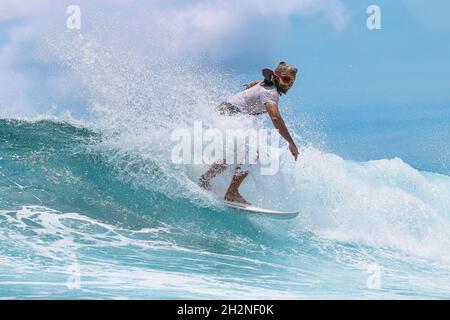 Homme portant un masque de dinosaure surfant avec planche de surf en mer Banque D'Images