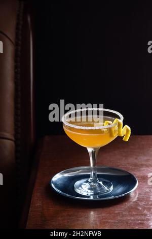 Cocktail de side-car avec rebord sucré en verre coupé dans un bar luxueux et sombre avec espace de copie Banque D'Images