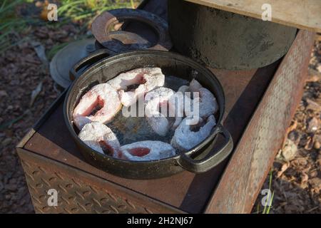 Poisson frit dans une poêle sur un poêle à bois à l'extérieur Banque D'Images