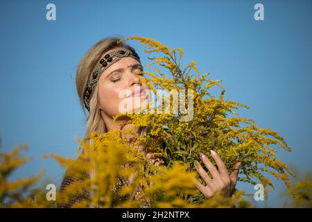 Un jeune herboriste se réjouit de l'odeur des fleurs d'or. Banque D'Images