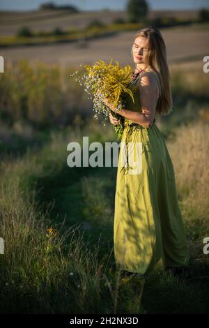 Un jeune herboriste amoureux d'un bouquet d'herbes se promette romaneusement dans les prés. Banque D'Images