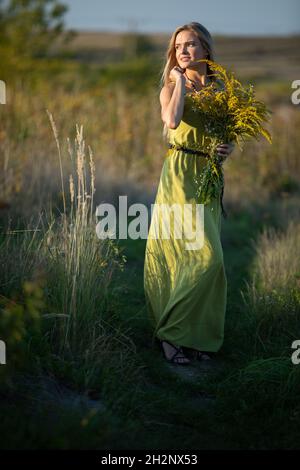 Un jeune herboriste amoureux d'un bouquet d'herbes se promette romaneusement dans les prés. Banque D'Images