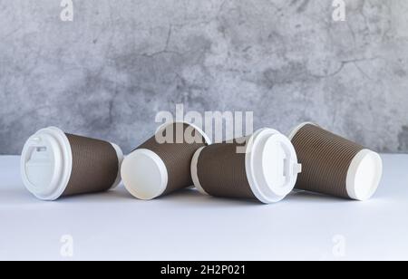 Quatre tasses à café en papier marron jetable avec bouchons blancs sur une table en bois.Boissons à emporter et vaisselle écologique Banque D'Images