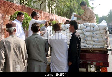 Les gens se rassemblent pour acheter des sacs de farine sur le prix des subventions d'un magasin de services publics mobiles vendu par le gouvernement de Sindh, comme le prix des articles généraux d'usage quotidien ont touché le ciel en raison de la hausse des prix dans le pays, au bord de la route à Hyderabad le samedi 23 octobre 2021. Banque D'Images