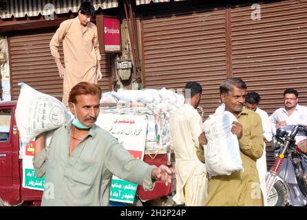 Les gens se rassemblent pour acheter des sacs de farine sur le prix des subventions d'un magasin de services publics mobiles vendu par le gouvernement de Sindh, comme le prix des articles généraux d'usage quotidien ont touché le ciel en raison de la hausse des prix dans le pays, au bord de la route à Hyderabad le samedi 23 octobre 2021. Banque D'Images