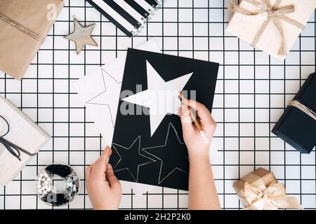 Idées créatives d'emballage de cadeaux.Cadeaux personnalisés.Plat moderne noir et blanc avec processus d'emballage cadeau. Ciseaux, boîtes d'artisanat enveloppées et Banque D'Images