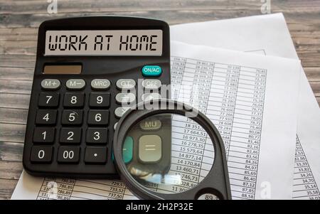 Le texte travaille à la maison sur l'affichage d'une calculatrice au-dessus de la table de bureau, qui repose sur une table en bois avec des documents Banque D'Images