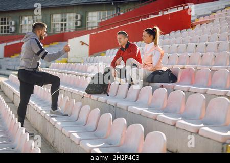jeune adulte caucasien beardy gars debout et parlant à couple souriant. concept entraîneur personnel Banque D'Images