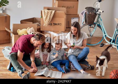 Famille caucasienne avec deux enfants et un chien qui s'installe dans une nouvelle maison Banque D'Images