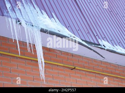 Gouttières brisées.Barrage de glace.Gros plan sur un nouveau système de gouttière cassé sans protection de toit pare-neige sur la construction de la maison.Les glaçons endommagent le toit a Banque D'Images