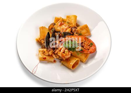 Pâtes Paccheri aux fruits de mer, pâtes italiennes typiques à la sauce tomate, moules, palourdes, calmars et crevettes dans une assiette blanche avec persil isolé sur du blanc Banque D'Images
