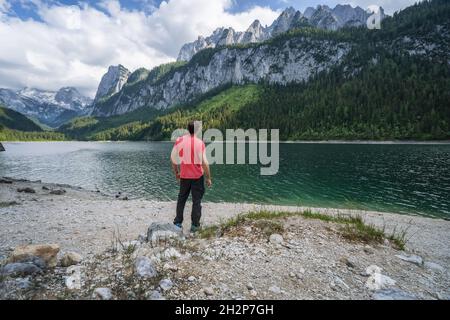 Homme appréciant les montagnes de Dachstein se reflète dans le lac de Gosau, en Autriche Banque D'Images