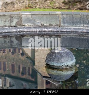Reflet de l'abbaye de Sainte-Foy dans le bassin de la fontaine du cloître, Conques, Aveyron, France Banque D'Images