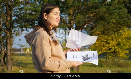 Une femme bouleversée à capuche regarde les affiches de chat manquantes dans le parc Banque D'Images