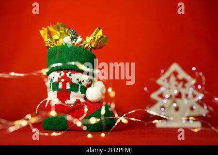 Nouvelle année et carte de Noël sur fond rouge.Botte de bonbons et de lumières de Noël.Contenu pour la Saint-Nicolas. Banque D'Images