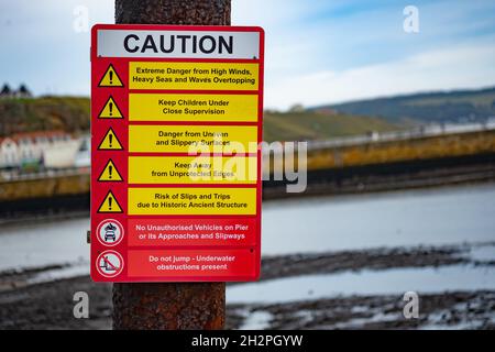 Whitby, Yorkshire, Royaume-Uni – octobre 20 2021.Panneau d'avertissement indiquant les dangers potentiels, ainsi que les règles d'accès, sur le port de Whitby Banque D'Images