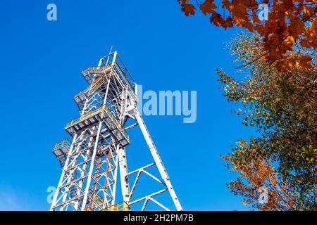 La tour de puits de mine 'Krystyn' dans l'ancienne mine de charbon 'Mical' à Siemianowice, Silésie, Pologne contre le ciel bleu.Magnifique arbre d'automne au premier plan. Banque D'Images