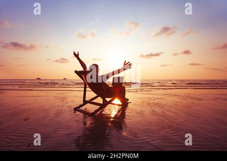 joyeux indépendant avec ordinateur portable travaillant sur la plage, concept de travail indépendant, le lieu de travail de bureau de rêve Banque D'Images