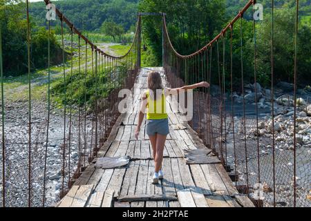 Un homme marche sur un pont suspendu en Géorgie Banque D'Images