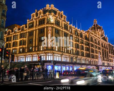 HARRODS LONDON TAXIS BLUR NOËL SHOPPING Harrods grand magasin au crépuscule avec des lumières de Noël shoppers et des taxis flous pour la location Knightsbridge Londres SW1 Banque D'Images