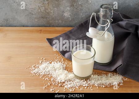 Lait de noix de coco végétalien et flocons sur une serviette gris foncé et une table en bois, alternative aux produits laitiers pour les animaux, espace de copie, foyer sélectionné, nar Banque D'Images