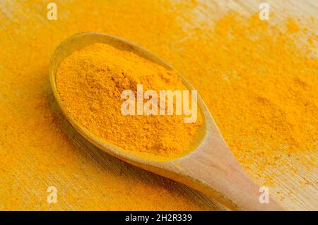 Curcuma frais en poudre aromatique dans une cuillère en bois sur fond en bois de bambou Banque D'Images