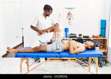 Deux hommes physiothérapeute et patient ayant la session de réadaptation étirant la jambe à la clinique Banque D'Images