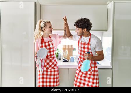 Un jeune couple souriant se fait un plaisir de laver les plats haut cinq à la cuisine. Banque D'Images