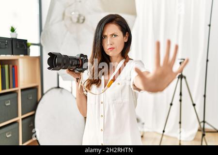 Belle femme caucasienne travaillant comme photographe au studio de photographie faisant un geste d'arrêt avec les mains paumes, expression de colère et de frustration Banque D'Images